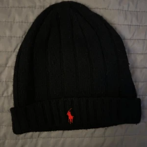Svart stickad mössa från Ralph Lauren - Snygg svart stickad mössa från Ralph Lauren (lamm ull) som är i gott skick. Kontakta gärna vid frågor ☺️
