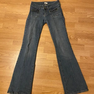 Blå/grå lågmidjade bootcut jeans - Ett par blå och ett par grå jeans från Nelly. Lågmidjade bootcut stl 38 använda några gånger de blå har en lagning men syns inte på ett annars men finns bild. Köptes för 700kr säljer för 400kr styck + frakt. 