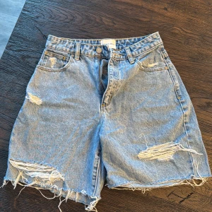 Jeansshorts från Abrand Jeans - Säljer ett par coola jeansshorts från Abrand Jeans. De är ljusblå med slitna detaljer och fransiga kanter för en avslappnad look. Perfekta för kommande sommardagar!
