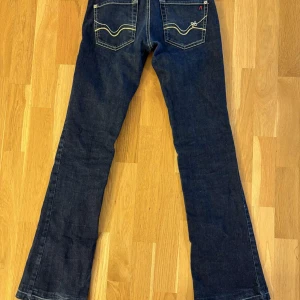 Mörkblå jeans från Replay - Snygga mörkblå jeans från Replay med bootcut-stil. Jeansen sitter lite tajt på mig som är 170cm och är lite förkorta. Jeansen har storlek W25 L32