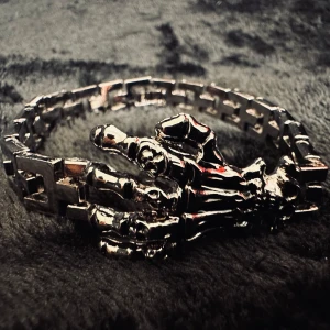 Silverfärgat armband med skelettdesign - Unikt armband i silverfärg med en detaljerad skelettdesign. Armbandet har en länkstil som ger det en robust och edgy look. Perfekt för att ge din stil en extra touch av attityd.