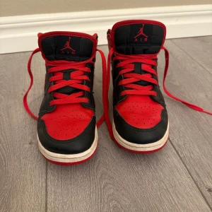 Nike Air Jordans i svart och rött - Snygga Nike Air Jordans i klassisk svart och röd färgkombination. Skorna har en hög design med snörning. Nya kostar runt 2000kr.  Det är i fint skick alltså knappast använda men har små skador som syns på bilderna.