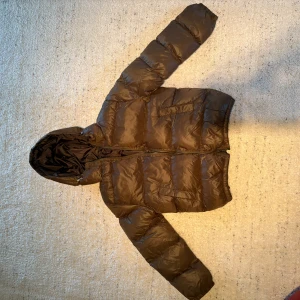 Mörk Grön pufferjacka med huva - Säljer en mörk pufferjacka med huva. Jackan har en dragkedja framtill och är quiltad för extra värme. Perfekt för kyliga dagar. Det är storlek s men sitter som xs. Den är helt ny aldrig använd då den var för lite gick inte att skicka tillbaka. Den är från Axel luxe. Nypris 800. 