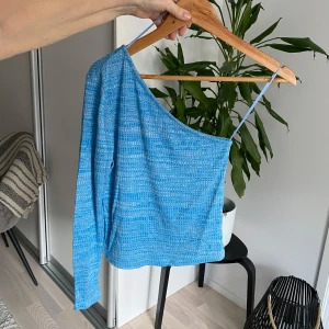 Blå oneshoulder topp - Snygg blå oneshoulder topp med ett unikt mönster. Perfekt för att sticka ut med sin asymmetriska design och tunna axelband. Ett måste för garderoben!