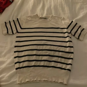 Randig tröja från Zara - Säljer en stilren vit och svart randig tröja från Zara. Tröjan har korta ärmar och en klassisk design som passar perfekt för en avslappnad look. Perfekt för dig som gillar tidlös stil!