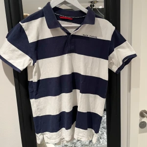 Randig pikétröja från Race Marine - Säljer en stilren randig pikétröja från Race Marine i blått och vitt. Tröjan har korta ärmar och en klassisk krage med knappar. Perfekt för en avslappnad och sportig look.