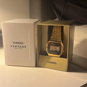Casio klocka - Säljer en stilren guld digital klocka från Casio med klassisk design. Klockan har en rektangulär urtavla med digital display och funktioner som alarm och datumvisning. Armbandet är i metall och justerbart för perfekt passform.