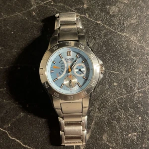 Casio Edifice herrklocka - Snygg Casio Edifice herrklocka med en stilren design. Klockan har en ljusblå urtavla med silverdetaljer och en robust boett i rostfritt stål. Armbandet är också i silverfärgat stål och har en säker låsning. Perfekt för den som vill ha en kombination av funktion och stil.