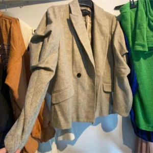 Beige kavaj från Zara - Snygg beige kavaj från Zara med klassisk design. Den har en knapp framtill och långa ärmar. Perfekt för en stilren look.helt ny