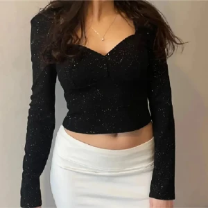 Svart glittrig topp - Snygg svart glittrig topp med långa ärmar och en v-ringad design. Perfekt för utekväll