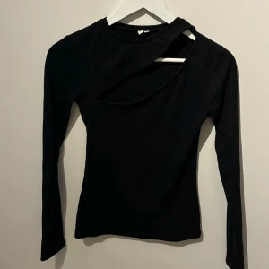Svart långärmad topp från NLY Trend - Snygg svart långärmad topp från NLY Trend med unik design med ett slitt över bröstet för en festligare känsla. Perfekt för att ge din outfit en modern touch. Tillverkad i ett mjukt och bekvämt material.