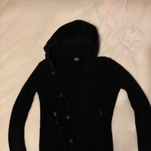 Svart stickad cardigan med pälsluva - Svart stickad cardigan med pälsluva som även går att ta av med dragkedja. Storleken är M men passar även S. Inga defekter. Priset kan diskuteras, hör av er vid funderingar (: