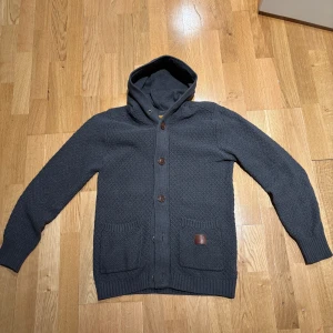 Mörkgrå cardigan med knappar  - Säljer en snygg mörkgrå stickad cardigan med knappar framtill. Inga defekter. Pris kan diskuteras. Hör av er vid funderingar.