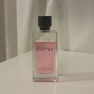May Be The Essentials Parfym - Säljer en elegant parfymflaska från The Essentials med namnet 'May Be'. Innehållet är en ljusrosa vätska som ger en fräsch och modern känsla.