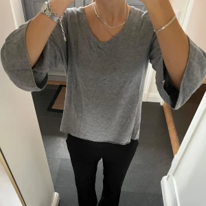 Grå stickad topp - Grå trekvartsärmad tröja med volanger från Made in Italy i fint skick. Kan inte hitta storlek men skulle säga M. Använd gärna köp nu!