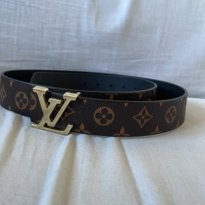 Brunt bälte med guldig logga - Jag säljer ett brunt bälte med mönster som har en guldig logga. Bältet är snyggt och passar till olika stilar. Pris kan diskuteras vid snabb affär.