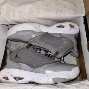 Grå Jordan Max Aura 4 - Snygga grå Jordan Max Aura 4 sneakers med vit sula och ikonisk Jumpman-logga. Skorna har en modern design med snörning och är perfekta för en sportig look.