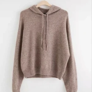 Beige stickad hoodie - Mysig beige stickad hoodie med långa ärmar och justerbar huva. Perfekt för kyliga dagar när du vill ha något bekvämt och stilrent. 
