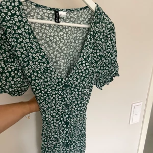 BLOMMIG KLÄNNING - Grön och vit mini klänning från H&M. Storlek 42 