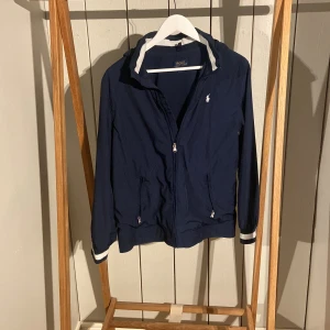 Mörkblå jacka från Polo Ralph Lauren - Säljer en snygg mörkblå jacka från Polo Ralph Lauren. Jackan är använd en gång.