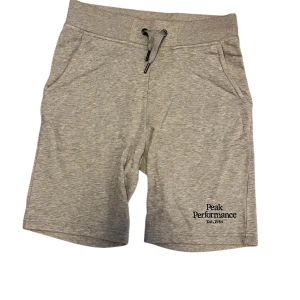 Grå shorts från Peak Performance - Snygga grå shorts från Peak Performance med snörning i midjan och broderad logga. Perfekta för en avslappnad stil.