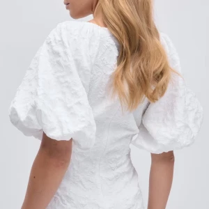 Vit klänning med puffärmar - Säljer en elegant vit klänning med puffiga kortärmar och v-ringad hals. Klänningen har en strukturerad yta som ger en unik look. Perfekt för sommarens alla tillfällen och perfekt nu till studenten! Säljer då jag köpte två stycken, klänningen är därmed helt ny med prislapp kvar! Slutsåld på hemsidan.🤍