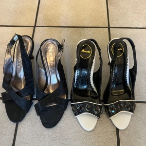2 par Svarta och vita klackskor med detaljer, säljes som paket - Två par eleganta klackskor i storlek 37. Ena paret är svarta med korsade remmar och en liten klack. Det andra paret är svartvita med glittriga detaljer på remmen och en smal klack. Perfekta för en stilfull look. Ena paret är använd en gång, den andra är helt ny.