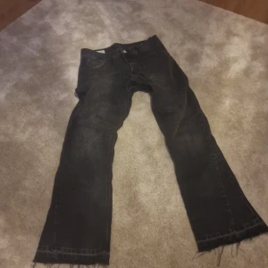 Svarta jeans från Zara - Snygga svarta jeans från Zara med en fransig nederkant. De har en klassisk femficksdesign och knappar i midjan. Perfekta för en avslappnad stil.