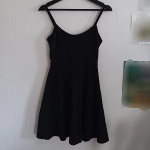 Svart klänning - Kläning i lite tjockare material. Väldigr skönt material. Justerbara axelband och relativt lång i kjolen. Har fått barkkåda på kjolen så har en fläck. Säljes då den inte kommer till användning längre [bara att skriva om frågor eller fler bilder!]