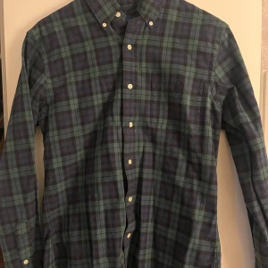 Rutig skjorta från Ralph Lauren - Snygg rutig skjorta från Ralph Lauren i grönt och blått. Skjortan har en broderad logga på bröstet och knappar framtill. Den är slim fit och långärmad, perfekt för en stilren look.