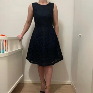 Marinblå ärmlös klänning - Snygg marinblå  ärmlös klänning med subtilt mönster. Perfekt för en elegant look. Klänningen har en klassisk passform som framhäver figuren och en rund halsringning.