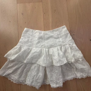 Vit kjol med volang och spetsdetaljer - Charmig vit kjol med vackra spetsdetaljer och volang. Perfekt för en somrig look.💗