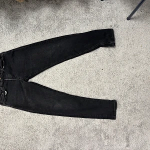 Svarta jeansbyxor - Snygga svarta jeansbyxor från Miké med en bekväm passform. De har en klassisk design med fem fickor och knappgylf. Perfekta för en stilren look.