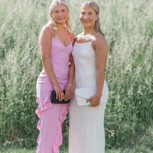 Vit glittrig långklänning - Säljer min balklänning som endast är använd 1 gång. En vit glittrig långklänning med smala axelband. Perfekt för bal eller fest. Blir väldigt fin i solljus med skimrande yta. Klänningen har en figurnära passform som framhäver silhuetten. 