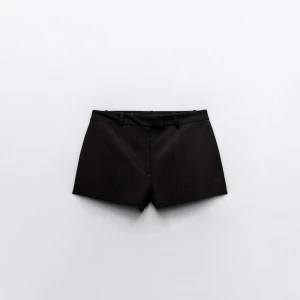 Shorts - Snygga svarta shorts från Zara med en stilren design. De har en lågmidjad passform och är tillverkade i ett syntetmaterial. Perfekta för en chic look med sina diskreta fickor och bälteshällor. Helt oanvända 