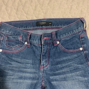 Blå jeans med stjärndetaljer - Snygga blå jeans från YMI Jeans med coola stjärndetaljer på bakfickorna. De har kontrasterande rosa sömmar som ger en unik touch. Perfekta för dig som vill ha något annorlunda i garderoben! Pris går att diskutera ✅