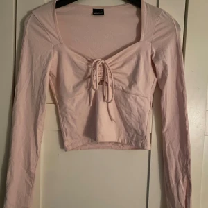 Rosa Långärmad tröja - Säljer en långärmad ljusrosa top från Gina med knytning fram. Använd fåtal gånger. Slits vid armarna💕