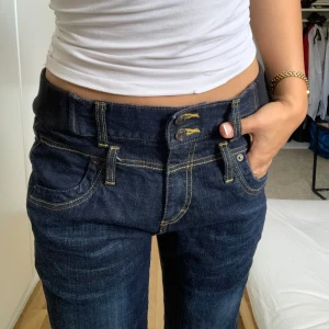 Lågmidjade jeans - Mörkblåa lågmidjade jeans med fina detaljer framtill och baktill! Står ingen storlek men skulle gissa på S och en liten M pga ”resårbandet” på sidan! Skriv för mer info & pris går att diskutera🌸 