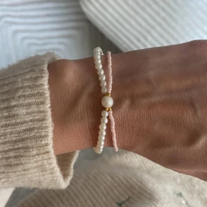 Pärlat armband med vita och rosa pärlor samt en sötvattenspärla - Jättefint pärlat armband med vita och rosa pärlor med en sötvattenspärla. Kommer med en vit sammetspåse. Perfekt gåva till sig själv eller att ge bort. 