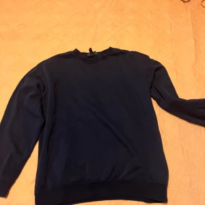 Mörkblå tröja från H&M loose fit - Säljer en mörkblå tröja från H&M i storlek M. Den har en avslappnad passform och är perfekt för både vardag och mysiga stunder. Tröjan är långärmad och gjord i ett mjukt material som känns skönt mot huden.
