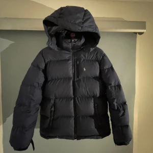 Ralph Lauren jacka - Blå Ralph Lauren dunjacka Perfekt inför vintern   Väldigt fint skick förutom några små hål på vänster sida som knappt synd och är lätt att laga, se bild 3 Storlek 160 men passar som xs Skriv för fler o bättre bilder
