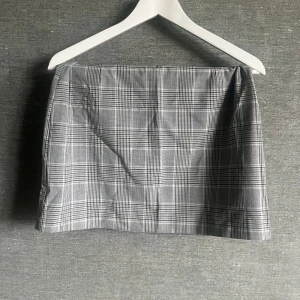 Grå rutig kjol från Lindex - Säljer en superfin grå rutig kjol från Lindex i storlek S. Perfekt för både vardag och fest! Kjolen har en klassisk passform och är gjord i ett bekvämt material. Den är i ett stilrent rutigt mönster som aldrig går ur tiden. Passar perfekt till en enkel topp eller en mysig stickad tröja.