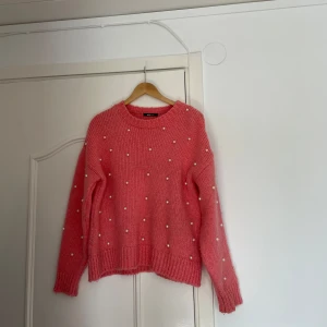 Rosa stickad tröja med pärlor - Superfin rosa stickad tröja från Gina med pärlor över hela. Perfekt för att liva upp garderoben! Den är långärmad och har en mysig passform. Perfekt för kyliga dagar eller när du bara vill känna dig extra söt. 🧶✨