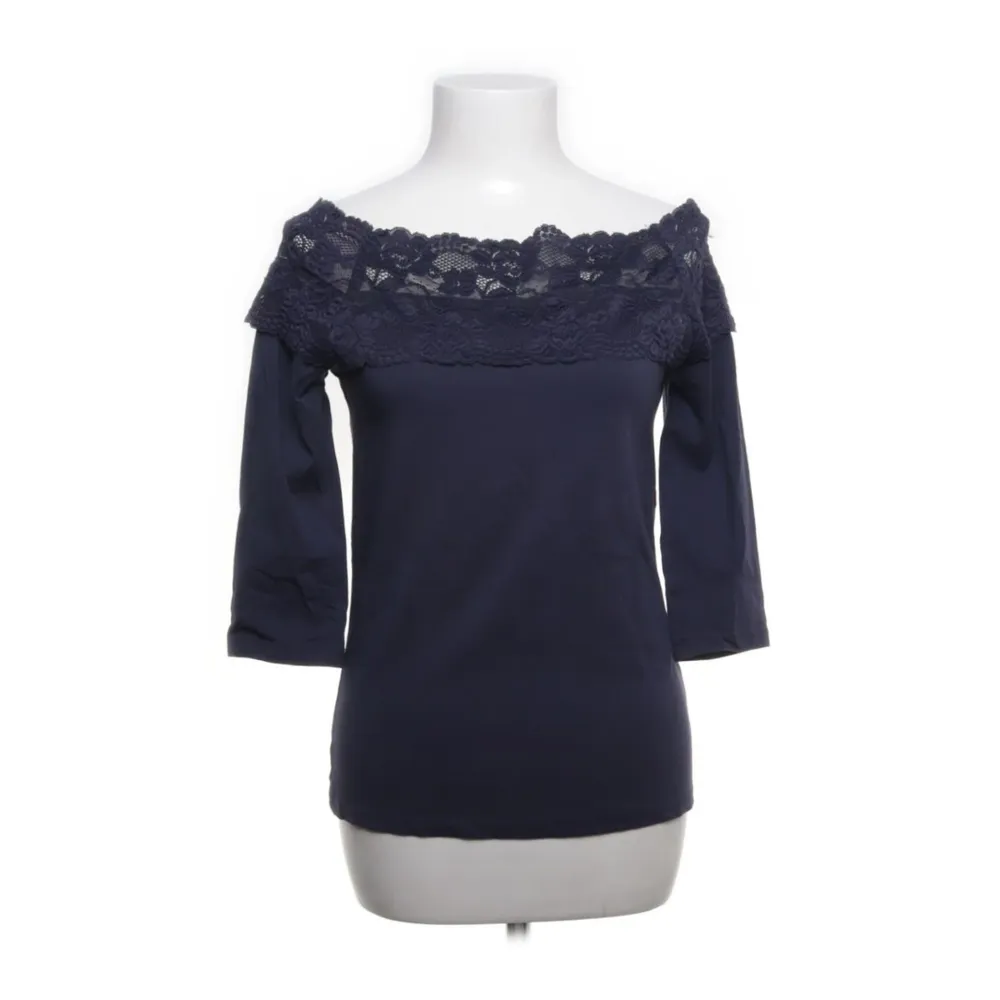 Snygg mörkblå offshoulder topp från s.Oliver med spetsdetaljer längs halsringningen. Perfekt för både vardag och fest! Trekvartsärmar ger en elegant touch. Passar bra till jeans eller kjol för en chic look.. Toppar.