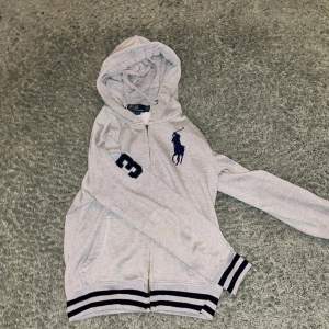 Säljer nu denna fina Ralph lauren zip hoodie i storlek S då den inte kommer till användning.                                              En bit av dragkedjan där man drar har gått av men den funkar fortfarande utan problem. Kan skicka bilder på den i dm. Tvivla inte på att höra av er vid funderingar!