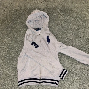 Ralph Lauren hoodie  - Säljer nu denna fina Ralph lauren zip hoodie i storlek S då den inte kommer till användning.                                              En bit av dragkedjan där man drar har gått av men den funkar fortfarande utan problem. Kan skicka bilder på den i dm. Tvivla inte på att höra av er vid funderingar!