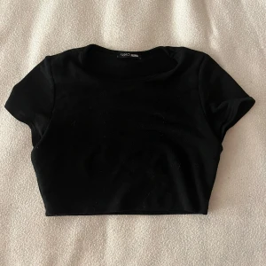 Svart croppad t-shirt från fashion nova  - Snygg svart croppad t-shirt från Fashin Nova med korta ärmar. Perfekt för att matcha med olika outfits!