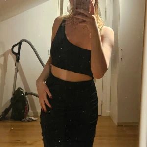 Festklänning - Hej, säljer denna svarta festklänningen. Den sitter jättefint på och båda delarna hör ihop och är sydda ihop, alltså är de inte separata. Det glittriga bandet la jag till just för att den delen inte ska åka ner! Men man kan ta bort den om man vill.