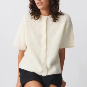 Vit stickad kofta med korta ärmar - Säljer en stilren vit stickad kofta med korta ärmar och knappar framtill. Helt oanvänd och slutsåld💕