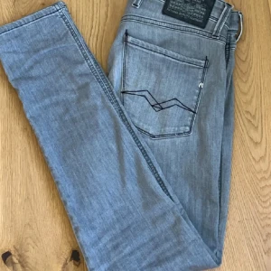 Grå jeans från Replay - Snygga grå jeans från Replay i modellen Anbass. De har en slim fit passform och är tillverkade i ett bekvämt material. De är självklart äkta! Storleken är 29/32